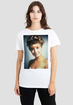 White cotton t-shirt featuring a large, colorful print of a smiling woman with curly hair and a tiara, set against a dark background.