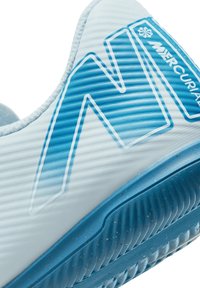 Białe i jasnoniebieskie buty sportowe z teksturowaną cholewką, wyraźnym logo N oraz niebieską podeszwą z rowkami i kropeczkami.