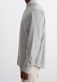 Camicia a maniche lunghe con bottoni in un motivo a quadri bianco e nero. Caratterizzata da un colletto, una vestibilità dritta e polsini con bottone. Tessuto morbido.