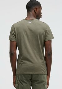 Olive green short-sleeve T-shirt, soft cotton material, crew neck, plain design, features a tag at the back, smooth texture.