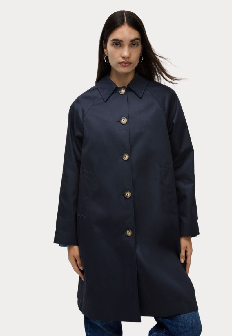Cappotto trench blu navale, realizzato in materiale liscio. Presenta un ampio colletto, bottoni frontali, tasche laterali e maniche lunghe.