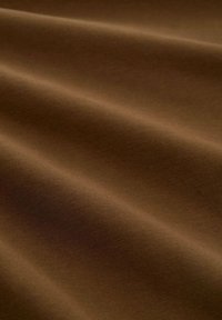 Bruine textielstof met een gladde, licht getextureerde oppervlakte, gekenmerkt door zachte plooien en een subtiele glans.