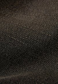 Σκοτεινός υφασμάτινος ιστός με υφή, που περιλαμβάνει ένα μείγμα μαύρων και σκούρων γκρίζων κλωστών. Το υλικό φαίνεται μαλακό και ανθεκτικό.