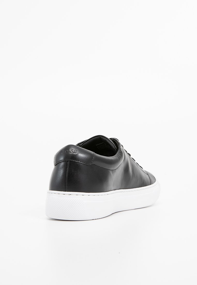 Sneaker in pelle nera con una superficie liscia, suola in gomma bianca e branding discreto sul tallone. Presenta lacci e un design arrotondato.