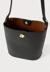 Borsa a secchiello in pelle nera con interno color cuoio, dettagli in oro, chiusura a scatto e tracolla regolabile. Texture liscia con design minimalista.