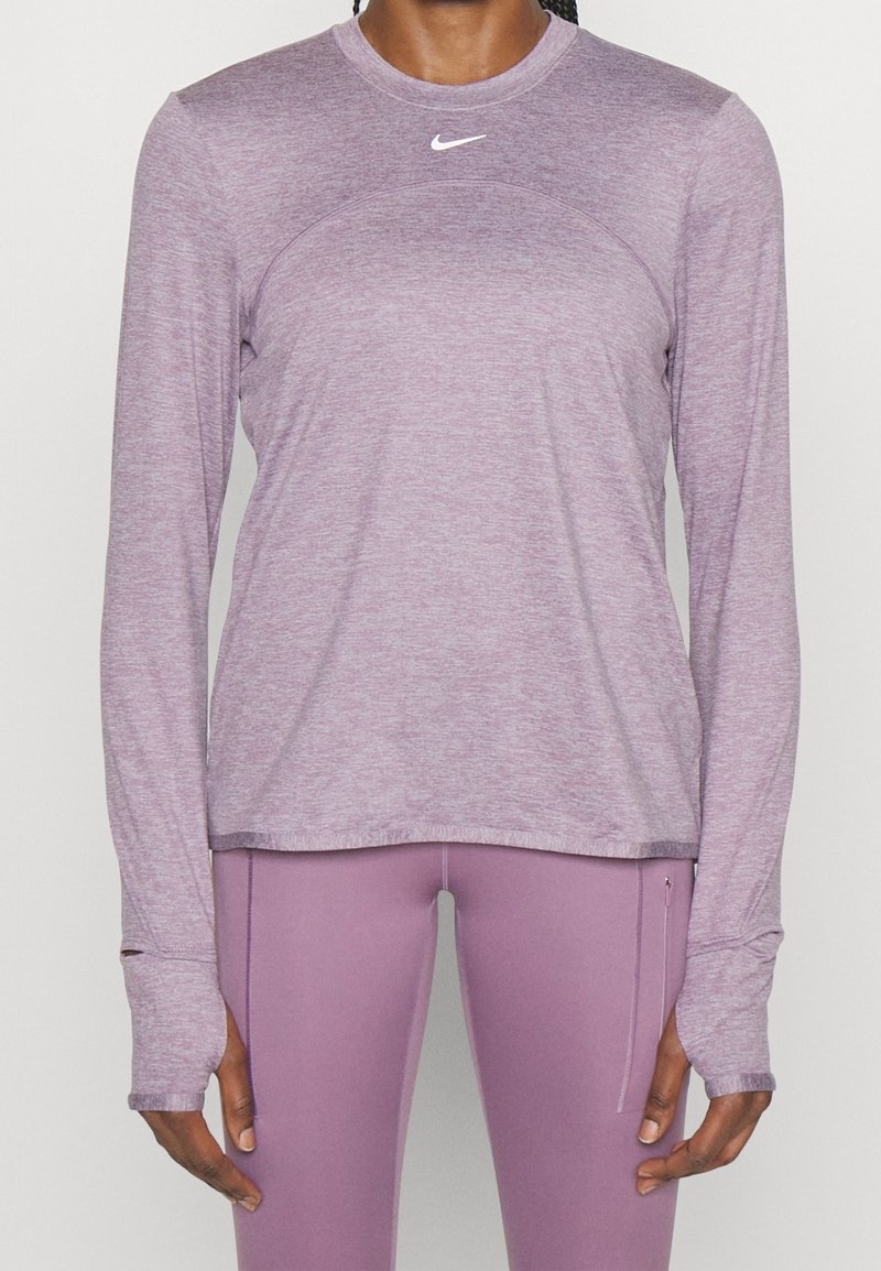 Person iført en lyse lilla langærmet træningstrøje og matchende tætsiddende leggings med hul til tommelfingrene og en lille lynlåslomme på låret.