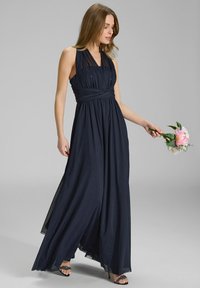 Lungo abito blu navy con scollo halter, corpetto arricciato e gonna fluida. Presenta dettagli in rete e accenti floreali a mano.