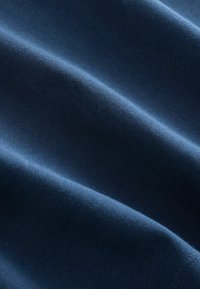 Navy blue cotton fabric with a smooth, textured surface, showing folds and subtle variations in light, indicating thickness and softness.