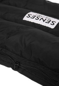 Schwarze Steppjacke mit wattierter Textur, mit Reißverschluss und einem weißen Etikett mit der Aufschrift "SENSES" auf der Vorderseite.