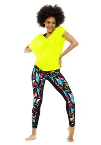 Neon yellow loose-fitting top paired with multicolored, patterned leggings featuring black base with geometric shapes in pink, blue, and green.