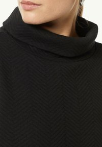 Maglione a collo alto nero con un motivo a spina di pesce testurizzato, in tessuto morbido e con un colletto arrotolato aderente per calore e comfort.