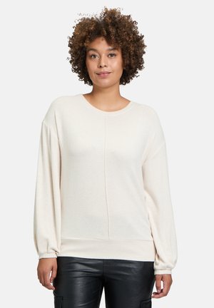 Helles beiges Pullover-Sweatshirt mit langen, ballonförmigen Ärmeln und Rundhalsausschnitt; weiche Textur und nahtloses Vorderdesign; getragen mit schwarzen Hosen.