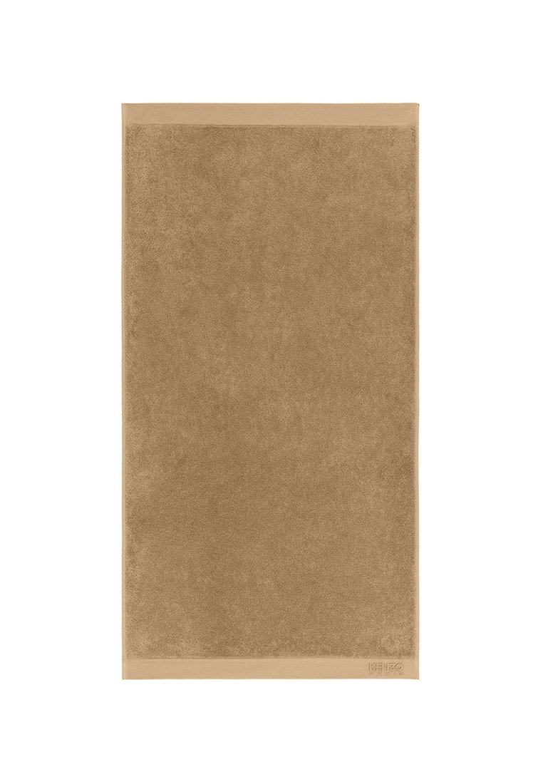 Serviette de bain marron avec une surface douce et texturée et une bordure lisse. Logo de la marque visible dans un coin. Forme rectangulaire.
