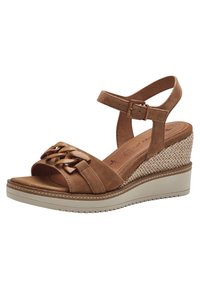 Brown suede wedge sandal with an ankle strap, woven bottom, and a wide front band featuring decorative bands and loops.