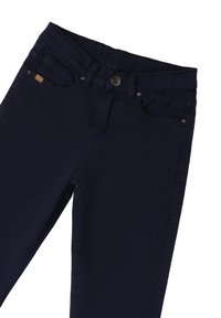 Vaqueros azul marino con un clásico diseño de cinco bolsillos, cierre de botón de metal y una tela suave y texturizada con detalles de costura mínimos.