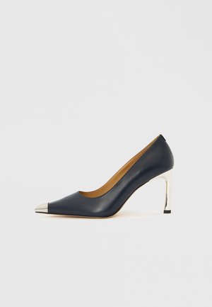 Navy lederen pump met een spits toelopende neus, voorzien van een zilverkleurige metalen neuskap en een glanzende zilveren naaldhak.