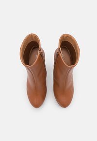 Paire de bottines en cuir marron avec fermetures éclair latérales, vues de dessus sur un fond blanc.