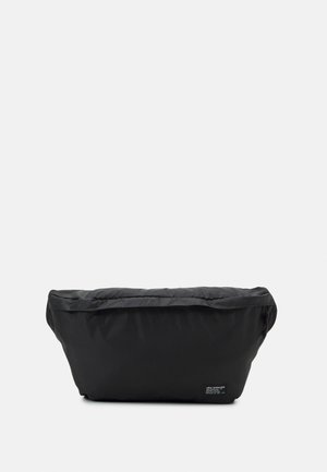 Schwarze Bauchtasche mit weicher, gepolsterter Textur und kleinem Levi Strauss-Logo-Patch vorne unten rechts.