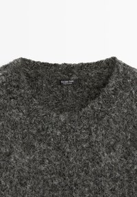 Mörkgrå, strukturerad tröja med rund halsringning och mjuk yta. Etiketten visar "Massimo Dutti," vilket anger varumärke och ursprung.