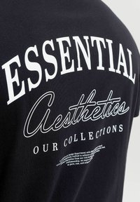 Μαύρο ύφασμα με λευκό κείμενο που γράφει "ESSENTIAL Aesthetics OUR COLLECTIONS" και μικρότερο διακοσμητικό κείμενο από κάτω.