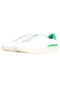 Sneakers bianchi in pelle con texture liscia, con accenti verdi sul tallone e sul lato, e suola in gomma piatta.