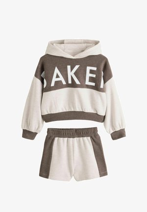 Tweekleurige bruin-beige kinderhoodie en shortset, met "BAKER" gedrukt over de borst van de hoodie.