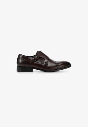 Scarpa da città in pelle marrone con un design elegante, dotata di doppie fibbie metalliche, punta affusolata e tacco nero basso.