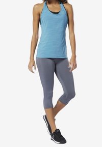 Light blue athletic tank top with textured stripes, paired with grey 3/4 leggings and black sneakers. Each piece designed for active wear.