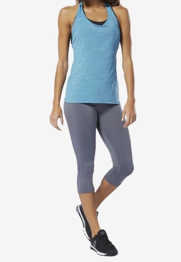Light blue athletic tank top with textured stripes, paired with grey 3/4 leggings and black sneakers. Each piece designed for active wear.