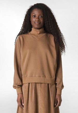 Brun, blødt stof sweatshirt med høj krave og ribbede manchetter, parret med en struktureret brun kordfløjlsskjørt med vertikale striber.