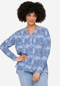 Blusa azul estampada con cuello en V, cierre de botones en la parte delantera y mangas largas. Presenta un ajuste holgado y aberturas laterales, fabricada en un tejido ligero.