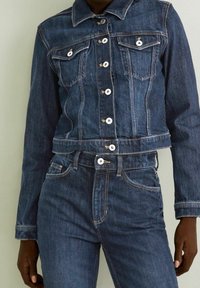 Denim jacket and matching jeans in dark blue wash. Jacket has silver hardware, two breast pockets, and cropped design.  Jeans feature a high waist.