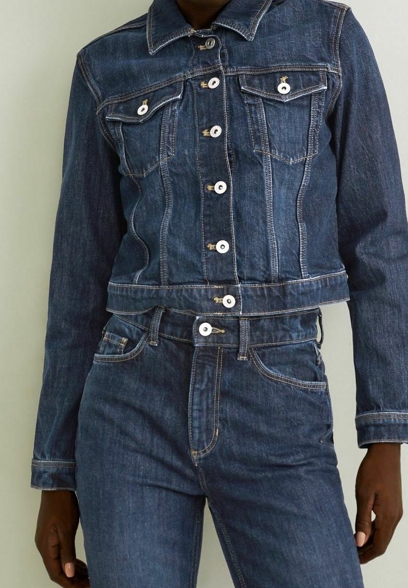 Denim jacket and matching jeans in dark blue wash. Jacket has silver hardware, two breast pockets, and cropped design.  Jeans feature a high waist.