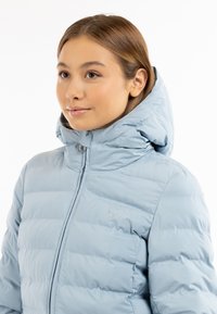 Giacca imbottita blu chiaro con cappuccio, caratterizzata da un design trapuntato, una zip frontale e un piccolo logo a cuore ricamato sul petto.