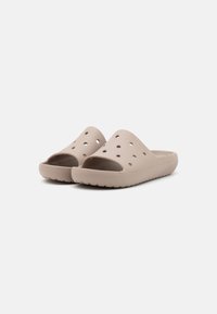 Sandali aperti beige con punta scoperta e ritagli laterali, realizzati in materiale morbido, dotati di una suola testurizzata per aderenza e comfort.