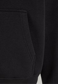 Black sweatshirt with a kangaroo pocket and ribbed hem. Soft fabric with a smooth, thick texture. Seams visible along the edges.