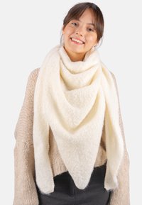 Écharpe crémeuse en couleur crème, confectionnée dans un tissu doux et texturé, présentant une forme triangulaire et un style drapé avec des extrémités effilées.