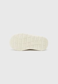 Sko såle i et teksturert beige materiale med et mønstret dekkdesign, som har dybde og spor for grep. Indentert merkevare synlig.