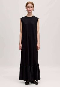 Schwarzes ärmelloses Maxikleid aus weichem Stoff, mit einem Rüschensaum und einer lockeren Silhouette. Einfacher runder Ausschnitt und knöchellanges Design.