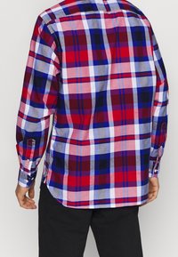 Camisa a cuadros roja, azul y blanca con botones, de manga larga, con dobladillo curvado y puños con botones, confeccionada en algodón.