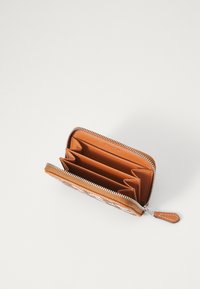 Portefeuille zippé en cuir tan avec une organisation interne comprenant plusieurs emplacements pour cartes et une texture lisse. Détail de fermeture éclair et de tirette en argent.