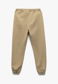 Beige stræk joggers med elastisk talje og afsluttede sømme. Glat tekstur, tapered design med stikninger og en afslappet pasform.
