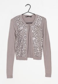 Svetle šedý kardigan s dlouhými rukávy, s přední částí zdobenou flitry. Měkký pletený materiál s žebrovanými detaily na manžetách a dole.