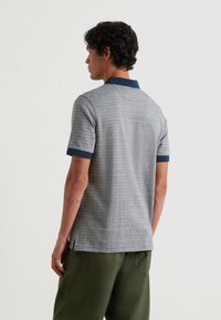 Polo shirt a righe grigie con colletto e polsini blu navy, maniche corte, orli laterali con spacco e una trama di cotone liscia.