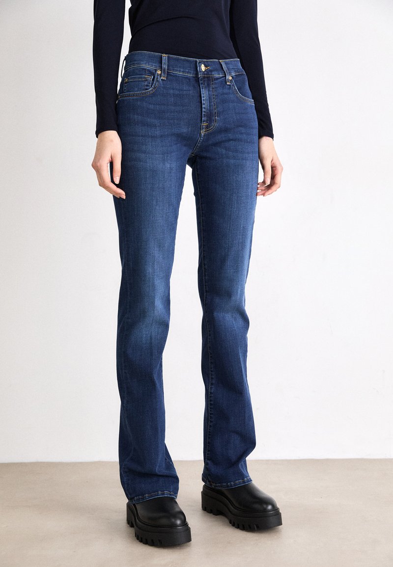 Dark blue straight-leg jeans made from denim, featuring front pockets, golden stitching, and a classic zip fly with button closure.