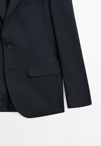 Granatowa marynarka dopasowana, o gładkiej fakturze, z pojedynczym zapięciem na guzik oraz eleganckim, strukturalnym designem. Posiada kieszeń na piersi oraz boczne rozcięcia.