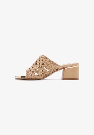Sandale à enfiler beige tissée avec un talon bloc. Elle présente une partie supérieure tressée et une semelle intérieure lisse. Le talon a une finition brillante.