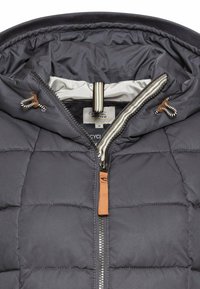 Marineblauer Puffermantel mit Kapuze, ausgestattet mit einem Reißverschluss, braunen Lederakzenten und gestreifter Innenauskleidung. Durchgehend gesteppte Textur.