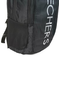 Mochila negra con textura suave, que cuenta con un bolsillo de malla, un logo prominente y cierres de cremallera. Diseñada para ser duradera y funcional.