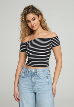 Top corto off-the-shoulder a righe bianche e nere con maniche corte, abbinato a jeans in denim azzurro chiaro a vita alta. Texture liscia.